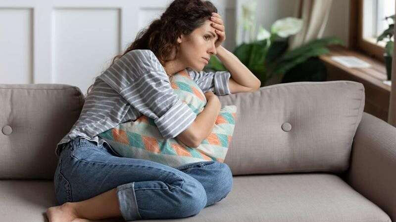 Femme triste assise sur un divan