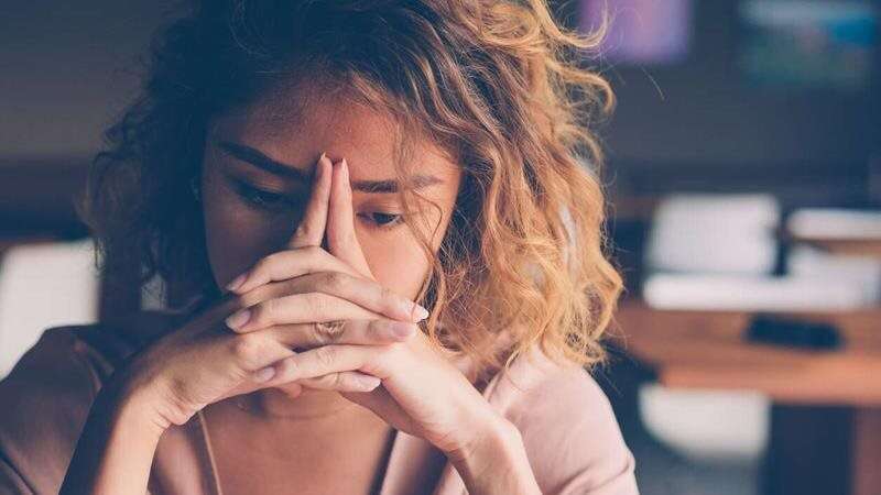 Concerned woman bending over her hands